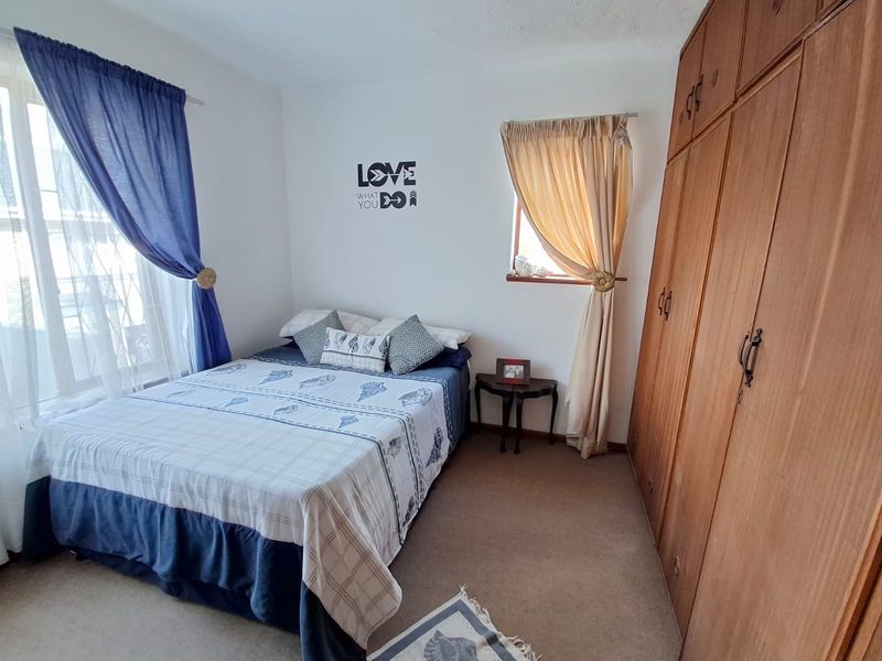 A functional bedroom featuring built-in wooden cupboards and carpeted flooring, offering a neutral space ready for personalization.