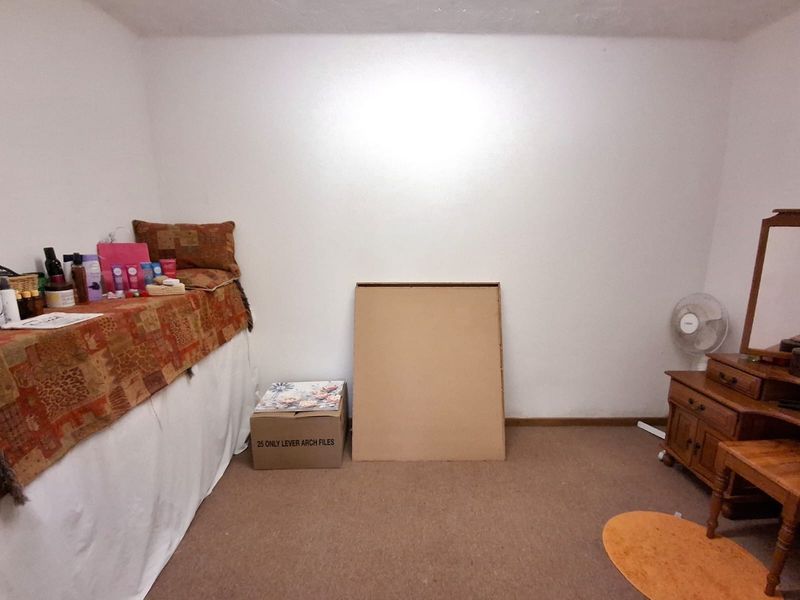A simple bedroom featuring neutral wall finishes and carpeted flooring, providing a blank canvas for potential interior design updates.