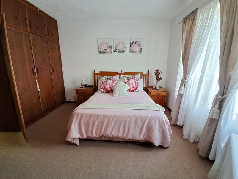 A spacious bedroom featuring built-in wooden wardrobes and neutral carpeting, offering a comfortable and functional living space.