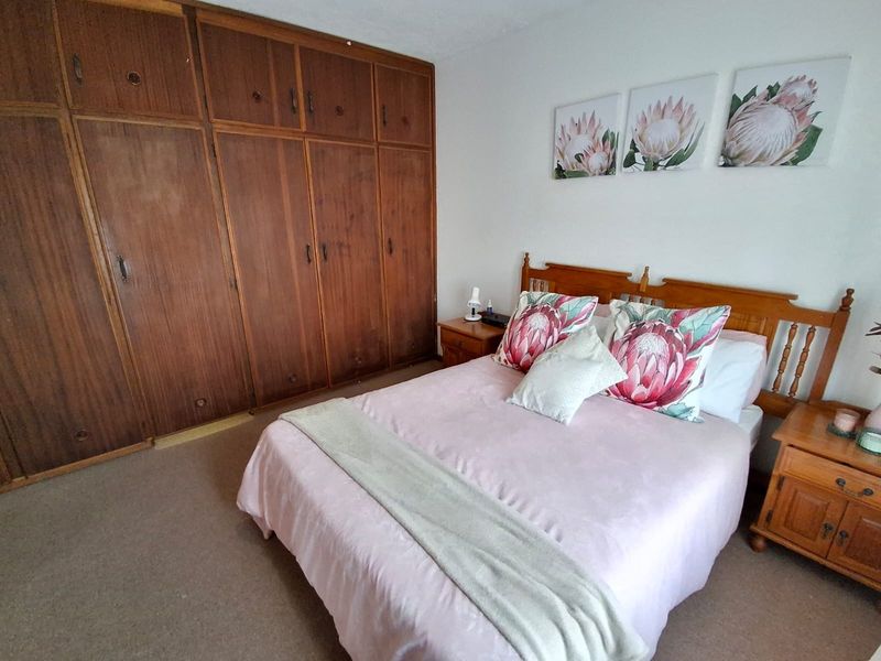 A bedroom featuring extensive built-in wooden cabinetry and carpeted flooring, offering a functional space with traditional storage solutions.