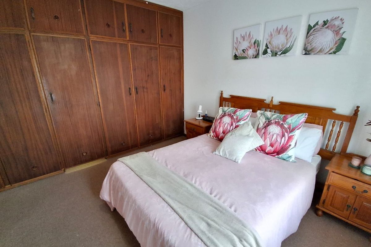 A bedroom featuring extensive built-in wooden cabinetry and carpeted flooring, offering a functional space with traditional storage solutions.