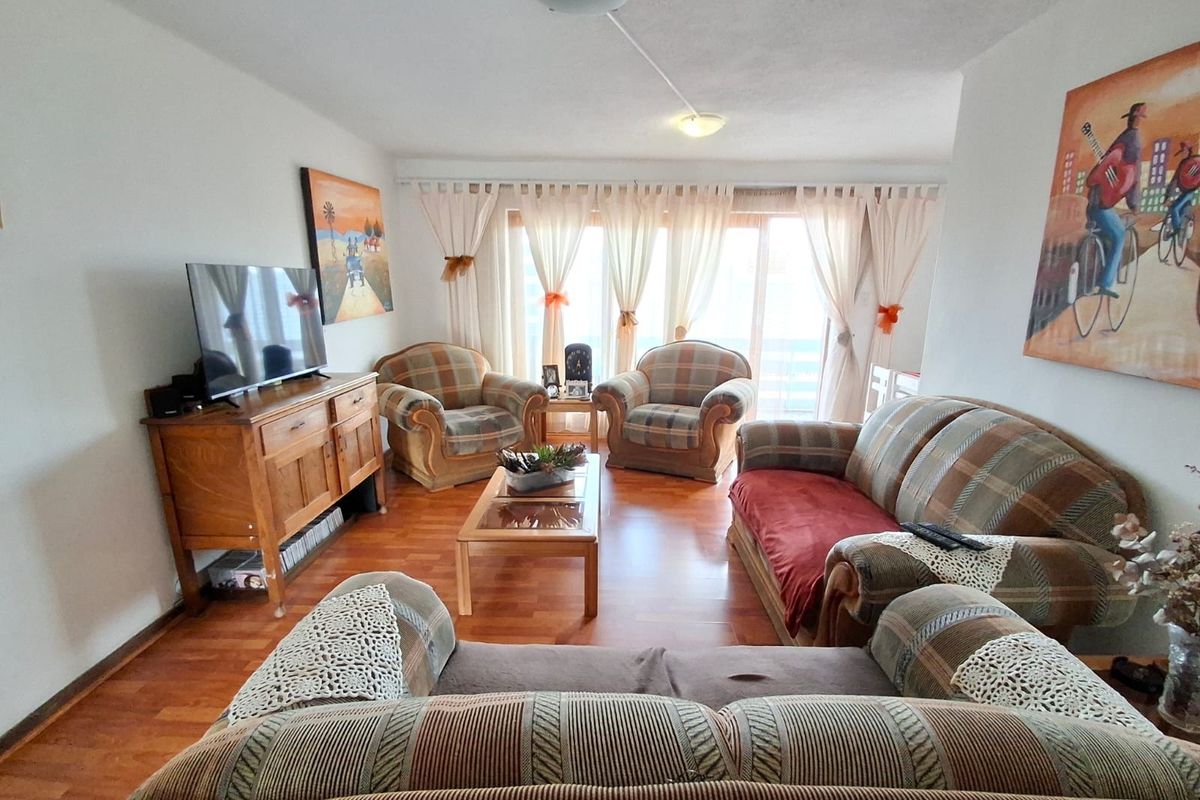 A comfortable living room featuring warm-toned laminate flooring and a large sliding glass door that provides natural light and access to the outdoors.