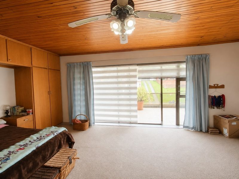 Spacious bedroom featuring built-in cupboards, a timber panelled ceiling, and large sliding glass doors providing direct access to an outdoor patio area.