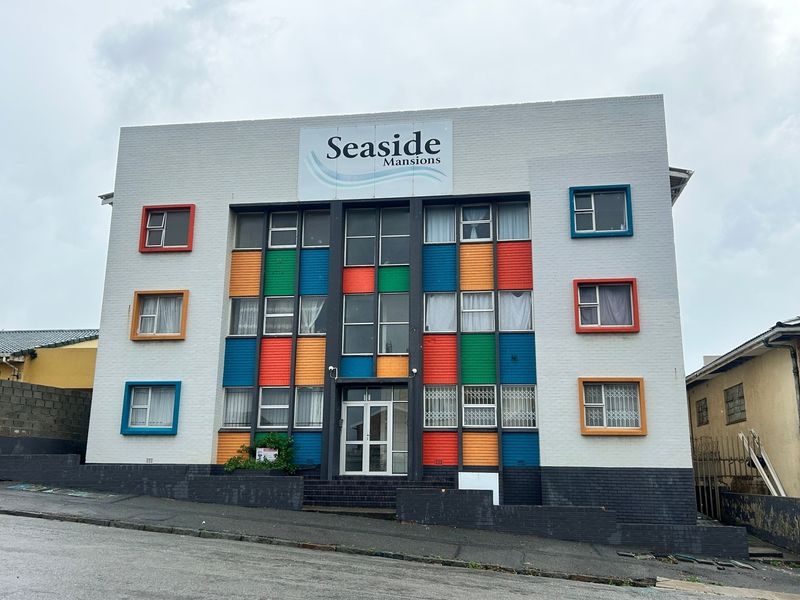 Front elevation of Seaside Mansions apartment building featuring a distinctive multi-colored facade, brick construction, and secure ground-level entrance.