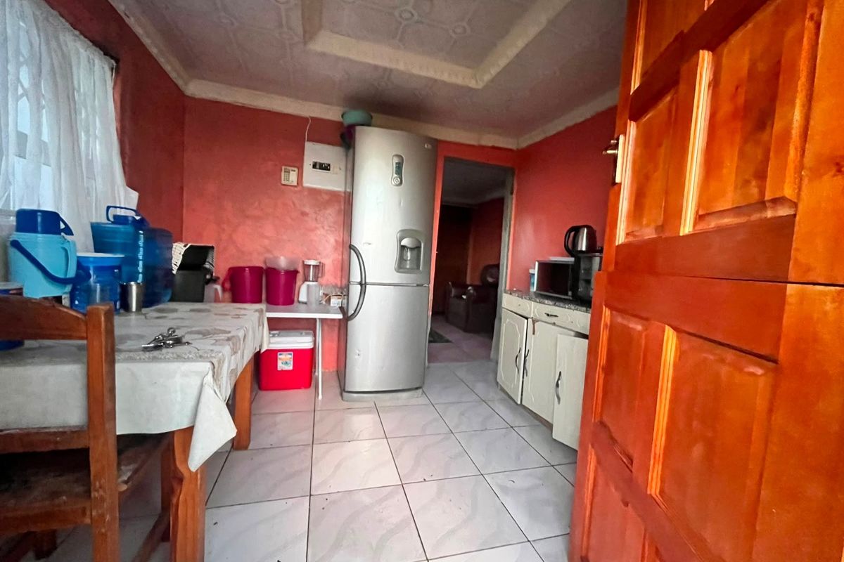 A compact kitchen featuring tiled flooring, built-in cabinetry, and a textured ceiling, offering potential for modernization and improved layout efficiency.