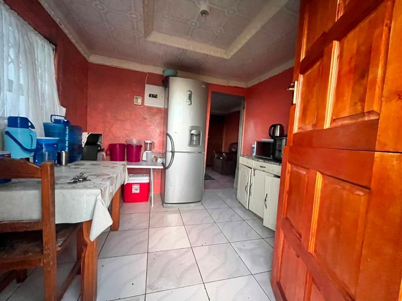 A compact kitchen featuring tiled flooring, built-in cabinetry, and a textured ceiling, offering potential for modernization and improved layout efficiency.