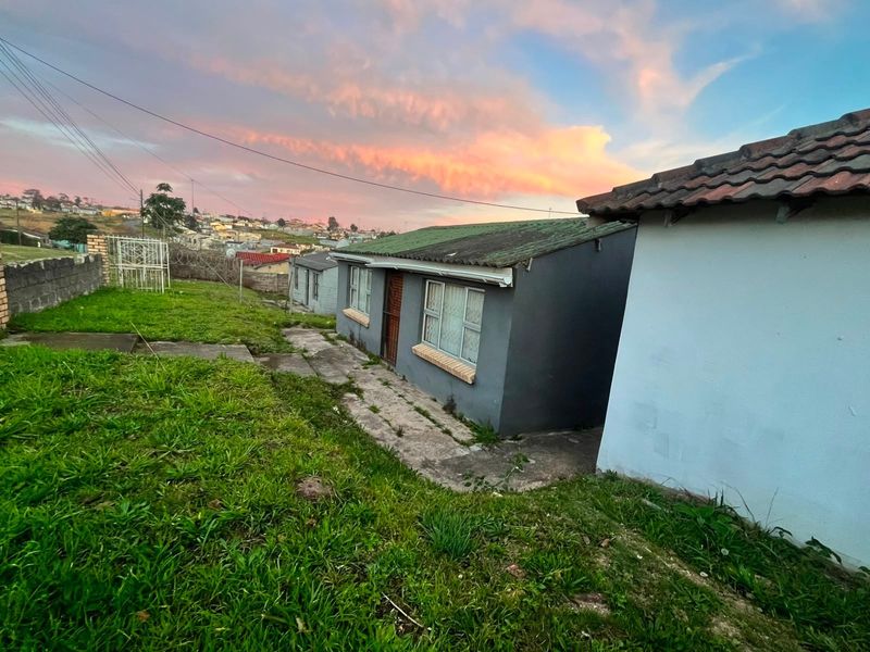 Rear view of the property showing the exterior facade, tiled roof, and surrounding garden area at sunset.