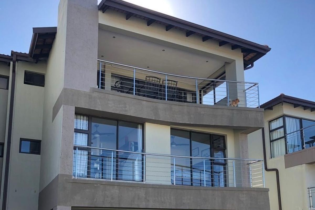 Rear elevation of a multi-story townhouse featuring stacked balconies with stainless steel balustrades and large sliding glass doors.