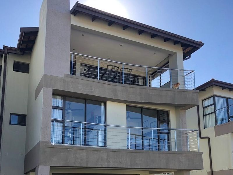 Rear elevation of a multi-story townhouse featuring stacked balconies with stainless steel balustrades and large sliding glass doors.