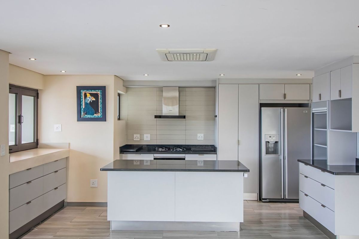 Modern kitchen featuring sleek cabinetry, stone countertops, a central island, and integrated stainless steel appliances with recessed lighting.