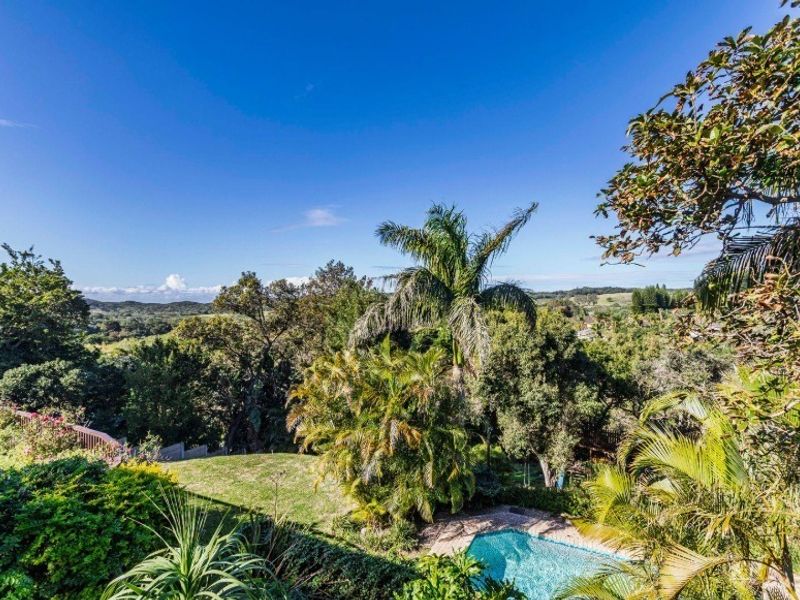 Elevated view overlooking a lush landscaped garden and a private swimming pool, set against a scenic natural landscape.