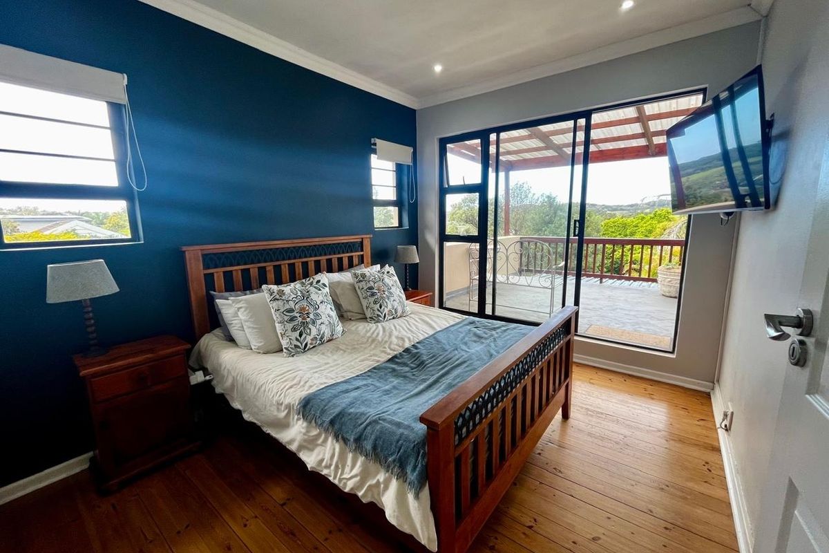 A well-maintained bedroom featuring hardwood flooring, a bold accent wall, and direct access to an outdoor balcony through sliding glass doors.