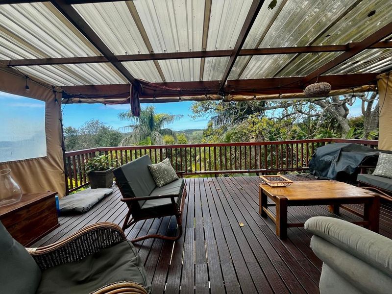 Covered outdoor timber deck featuring a pergola structure and balustrade, offering elevated views of the surrounding landscape.
