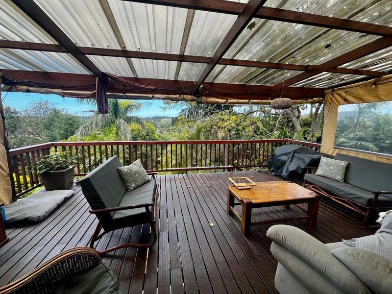 Covered outdoor timber deck featuring a pergola structure and balustrade, offering elevated views of the surrounding landscape.