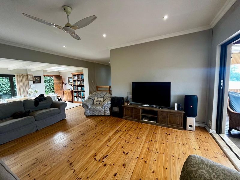 Spacious living room featuring polished timber flooring, recessed downlighting, and large sliding glass doors providing access to the outdoor area.