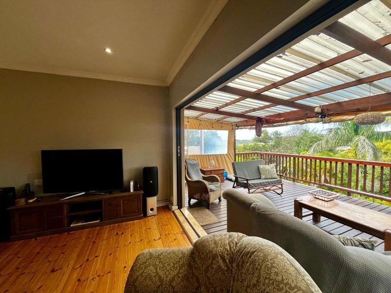 Open plan living area featuring polished timber floors and seamless transition to a covered outdoor timber deck with balustrade.