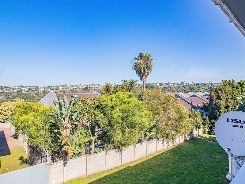 Elevated view overlooking the surrounding residential neighborhood, featuring a well-maintained lawn and established garden greenery.