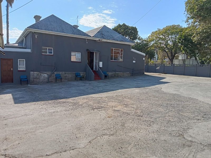 Front exterior view of the guest house featuring a large concrete driveway, stone foundation, and secure entrance with metal security gate.