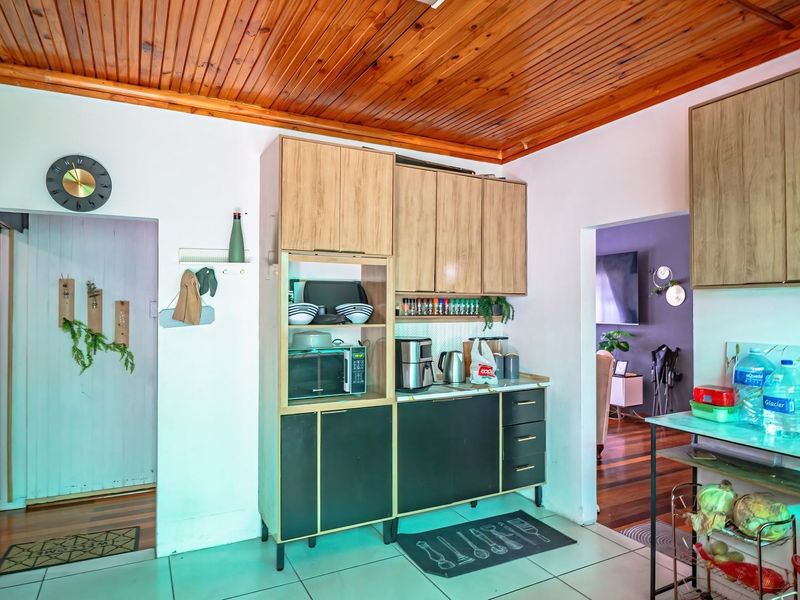 A functional kitchen area featuring wood-paneled ceilings, tiled flooring, and built-in cabinetry with a mix of light wood and dark finishes.