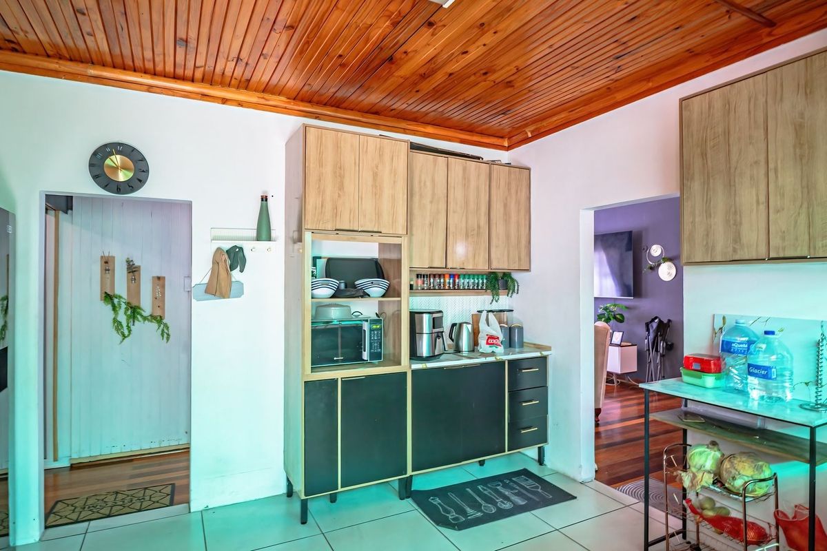 A functional kitchen area featuring wood-paneled ceilings, tiled flooring, and built-in cabinetry with a mix of light wood and dark finishes.