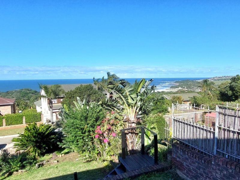 Elevated coastal view overlooking the surrounding neighbourhood, lush greenery, and the ocean horizon.