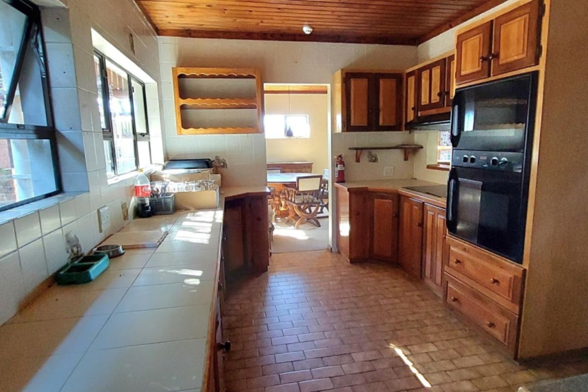 A functional kitchen featuring timber ceilings, tiled countertops, and built-in wooden cabinetry with an integrated double oven.