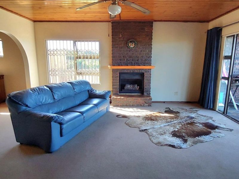 Spacious living room featuring a brick fireplace, timber ceiling, and large sliding glass doors providing access to the outdoor area.