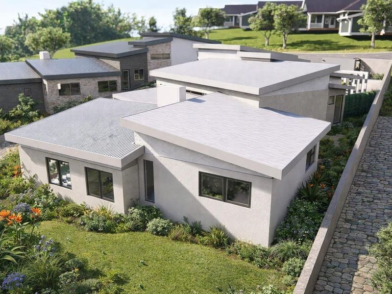 An aerial view of a modern residential property featuring a corrugated metal roof, stucco exterior, and landscaped garden surroundings.