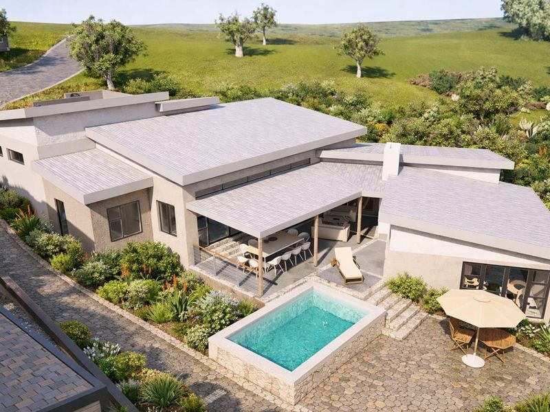 Aerial view of a modern residential property featuring a swimming pool, covered patio, and landscaped garden set within a scenic landscape.
