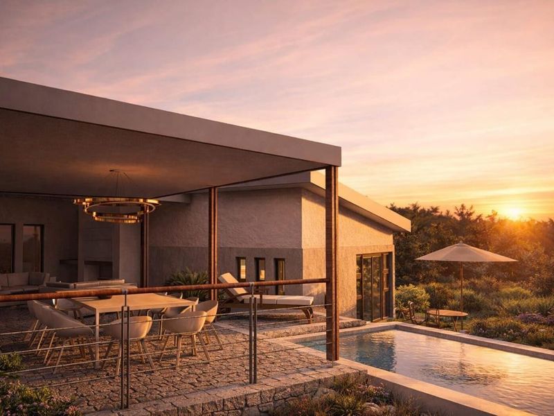 A luxurious covered patio area featuring stone paving, integrated lighting, and a seamless transition to an adjacent swimming pool at sunset.