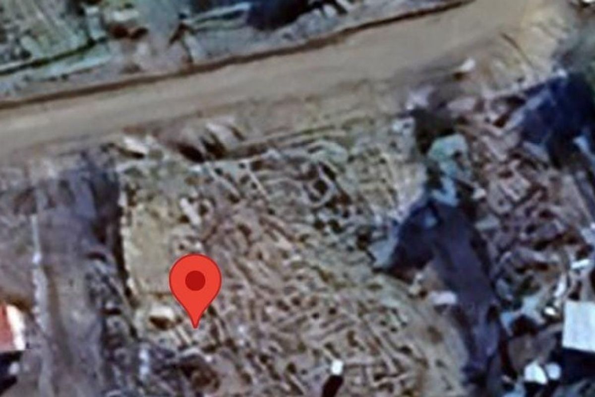 An aerial view of a vacant residential plot showing the surrounding terrain and access road.