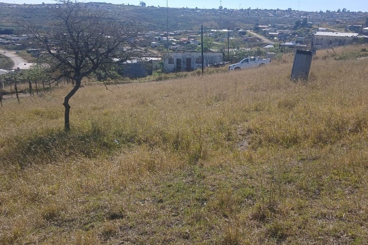 A view of a vacant residential plot featuring sloped terrain and surrounding neighborhood views.
