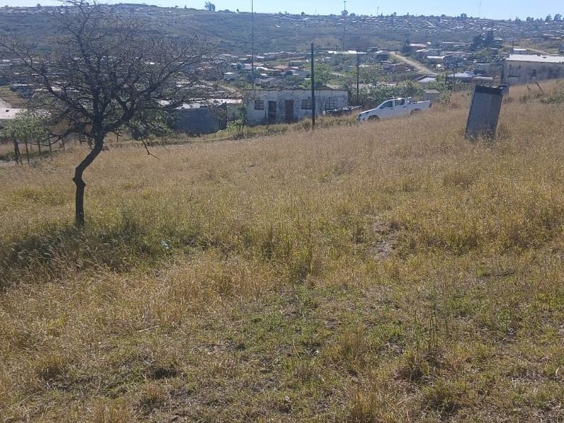 A view of a vacant residential plot featuring sloped terrain and surrounding neighborhood views.