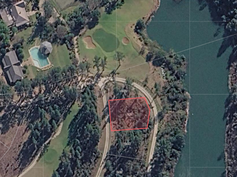 Aerial view of a vacant residential plot located within a golf estate, featuring proximity to a water body and established surrounding vegetation.