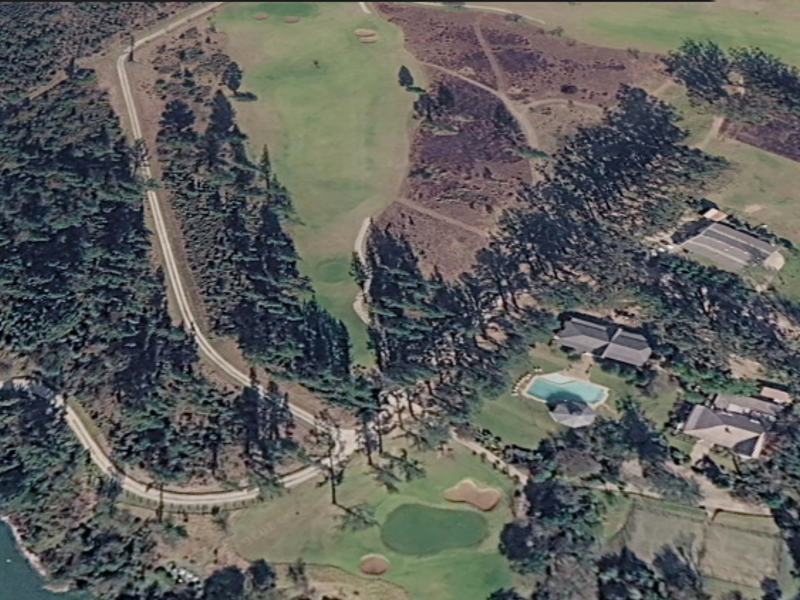 An aerial view of a residential property situated within a golf course estate, featuring a swimming pool and surrounding landscaped grounds.