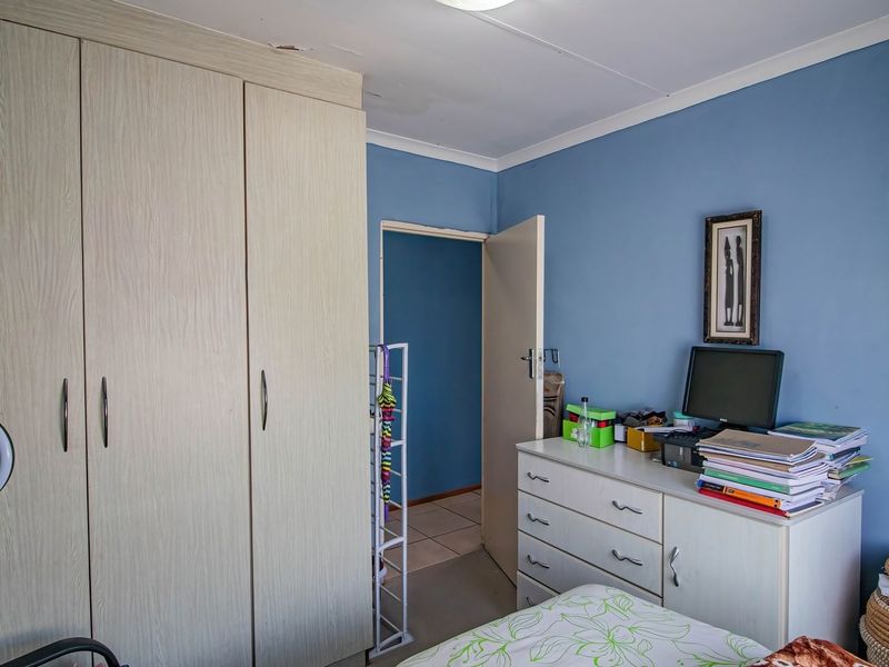 A bedroom featuring a large built-in wardrobe and blue painted walls, with visible ceiling damage near the cabinetry.