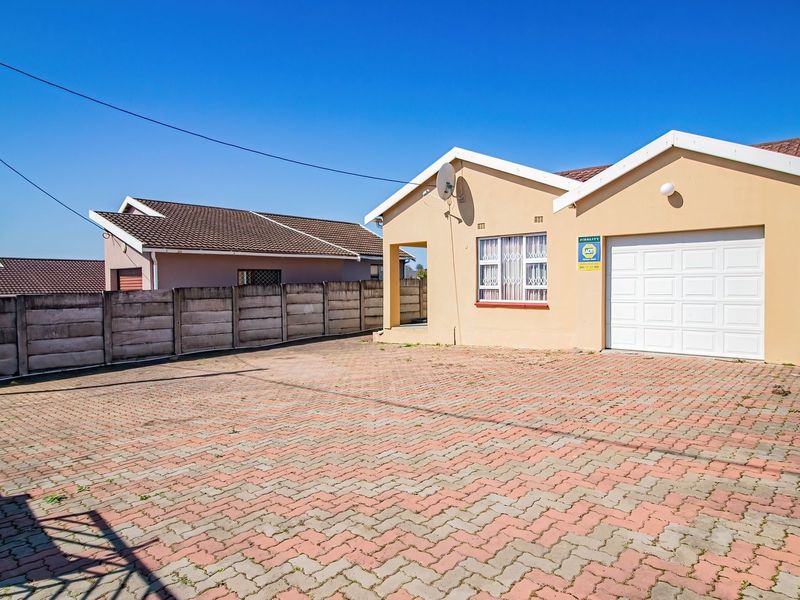 Front exterior view of a single-story house featuring a paved driveway, single garage, and secure boundary walling.