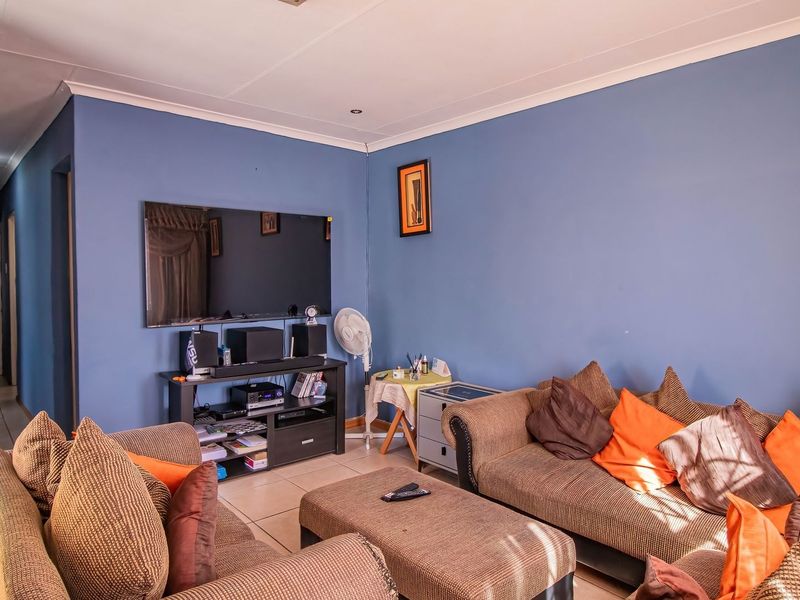 A comfortable living room featuring tiled flooring, recessed downlighting, and coved ceiling cornices, providing a functional and well-lit space for relaxation.