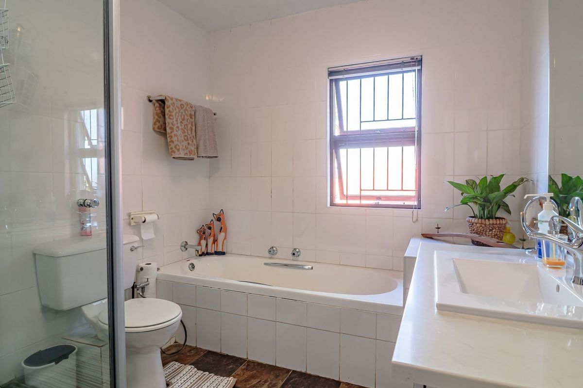 A functional bathroom featuring a built-in bathtub, separate shower enclosure, and a vanity basin with tiled wall finishes.