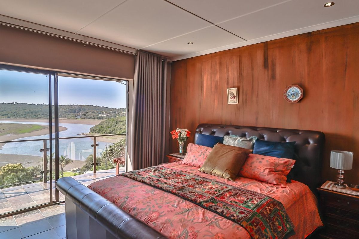 Spacious bedroom featuring a large sliding glass door that opens onto a balcony with scenic river and landscape views.