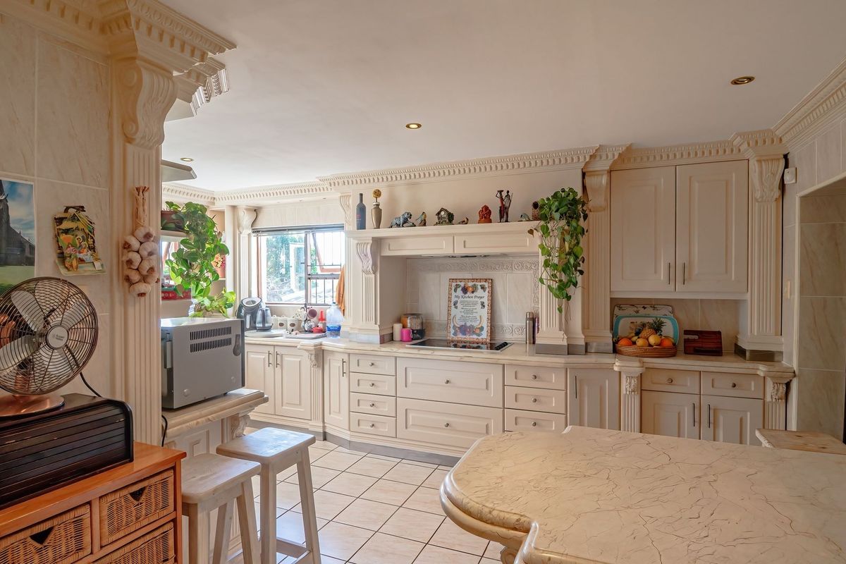 A traditional kitchen featuring ornate cabinetry, marble countertops, and ceramic tile flooring, accented with decorative corbels and crown molding.
