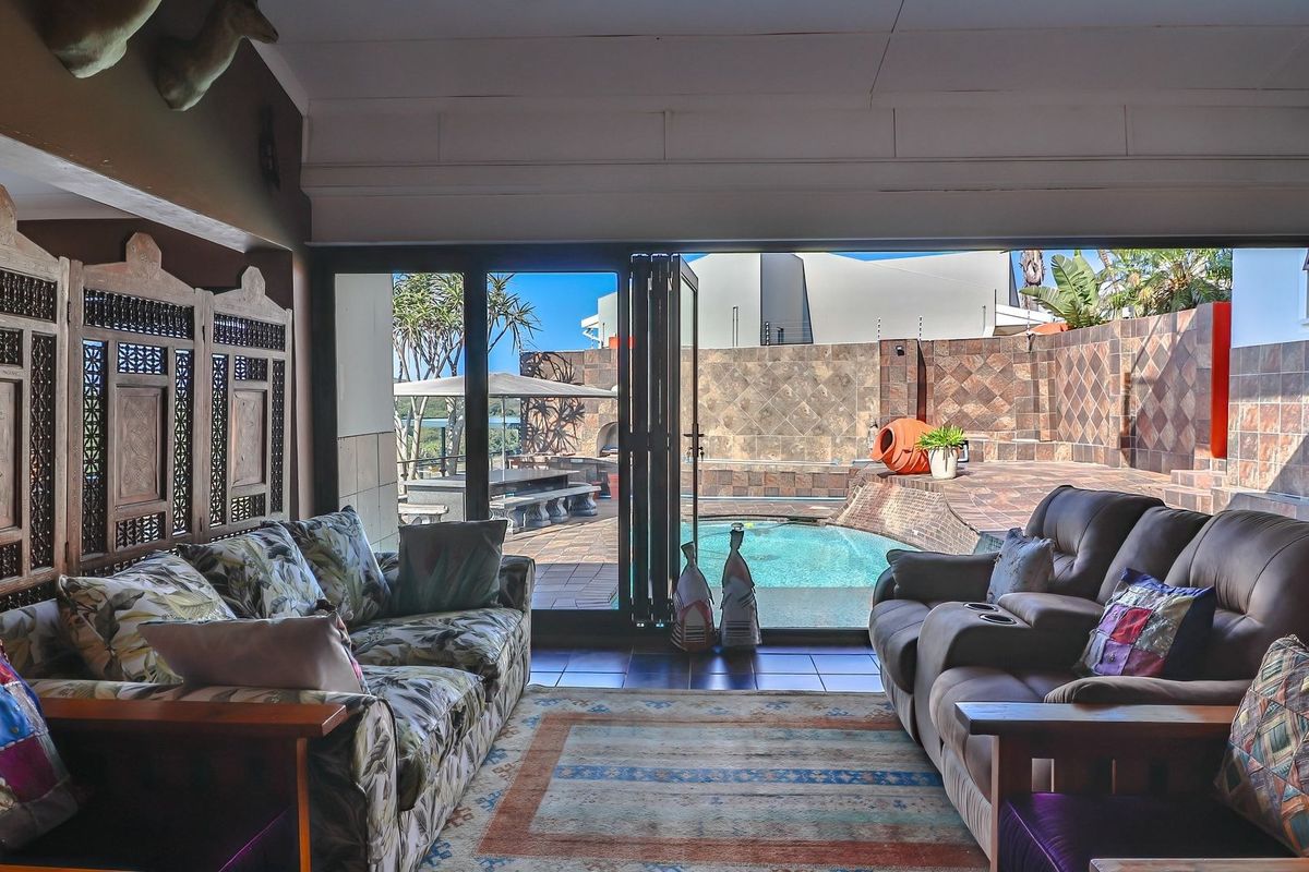 Spacious living room featuring large bi-fold glass doors that open directly onto a private patio and swimming pool area.