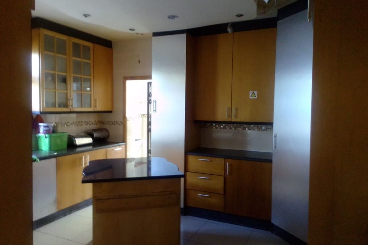A functional kitchen featuring wooden cabinetry, granite countertops, a central island, and tiled backsplash, offering ample storage and workspace.