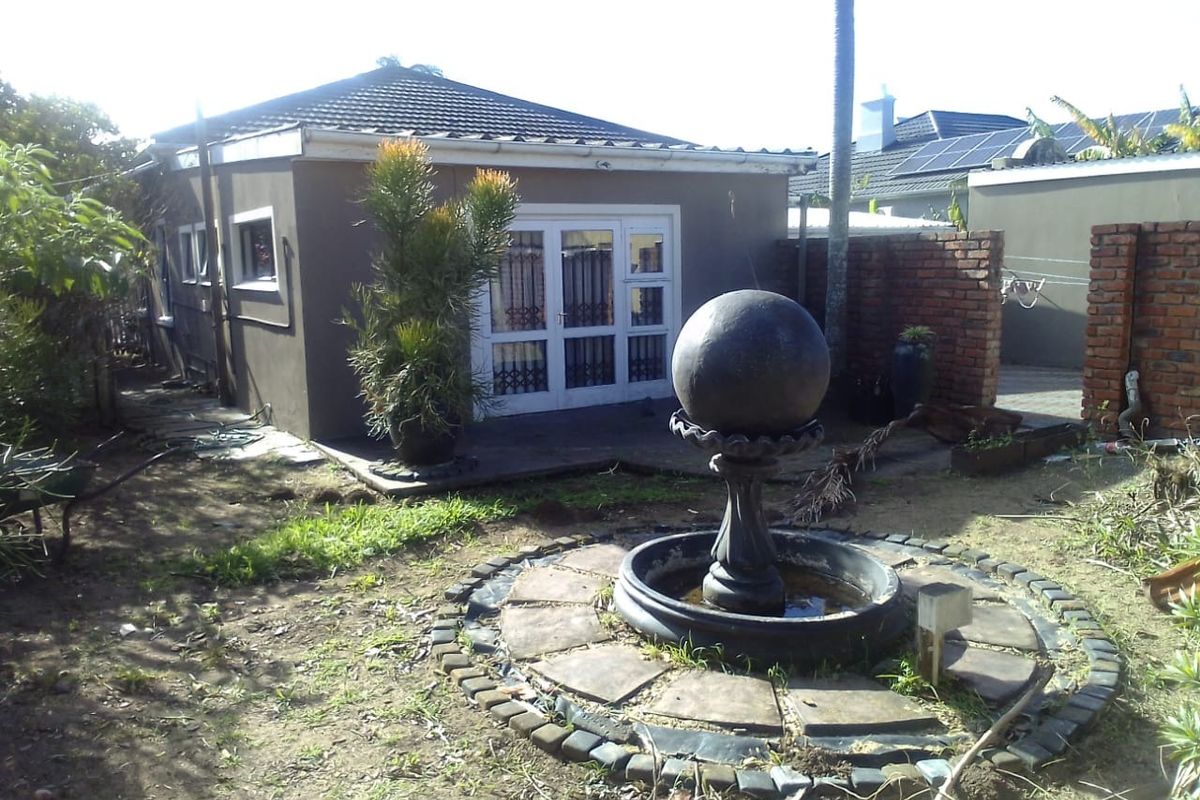 Rear garden view featuring a central water feature, paved border, and access to the main dwelling via white-framed french doors.