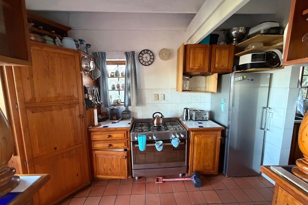 A rustic kitchen featuring wooden cabinetry, tiled countertops, and a gas stove, offering a traditional aesthetic with potential for modern updates.