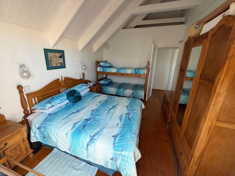 A bedroom featuring exposed timber ceiling beams, tongue and groove ceiling paneling, and warm timber flooring, providing a cozy and rustic atmosphere.