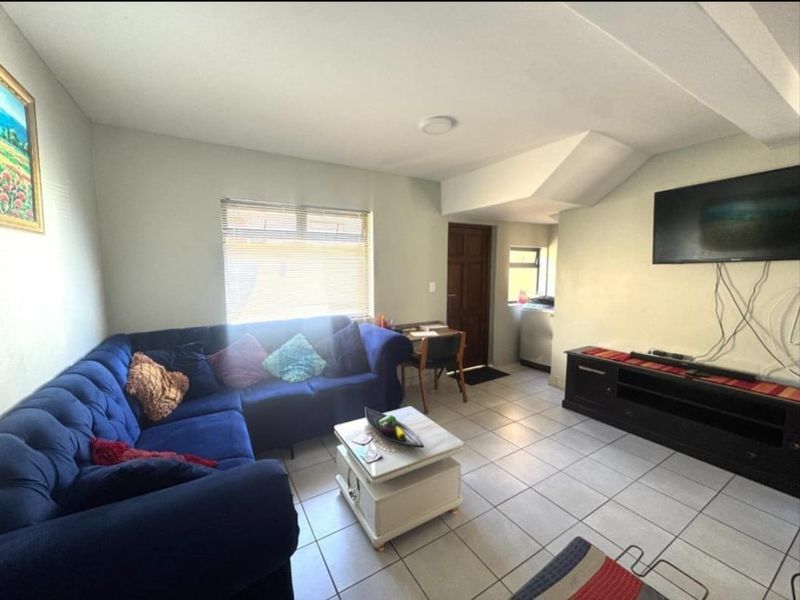 A living room featuring tiled flooring, venetian blinds, and recessed lighting, with a wall-mounted television setup.