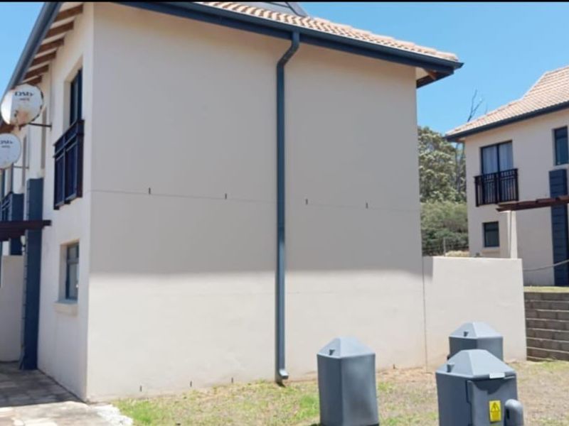 Exterior view of apartment units featuring tiled roofs, satellite dishes, and paved walkways with timber pergola structures.