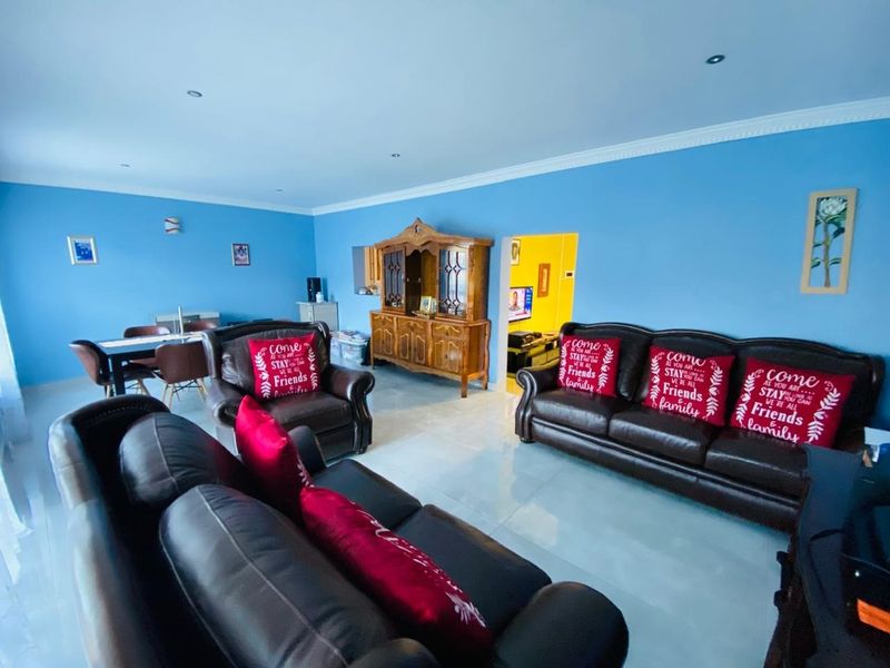Spacious open-plan living and dining area featuring tiled flooring, recessed downlighting, and decorative coved cornicing.