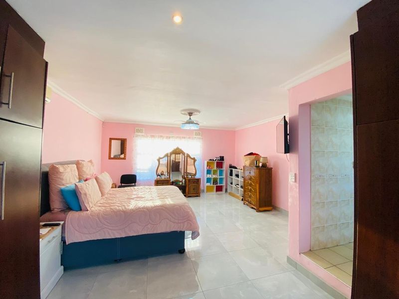 Spacious bedroom featuring tiled flooring, built-in cupboards, a ceiling fan, and direct access to an en-suite bathroom area.